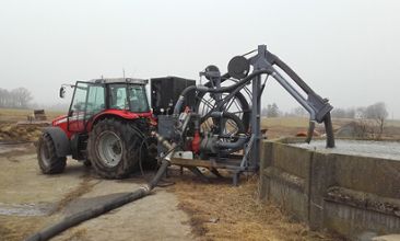 Traktor med pump nedsänkt i en flytgödselbehållare