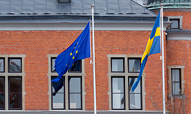 Svensk flagga och EU-flagga tillsammans utanför byggnad